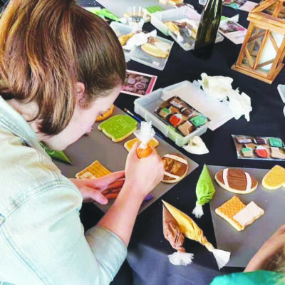 A girl concentrates intently as she decorates a sugar cookie with a bag of frosting