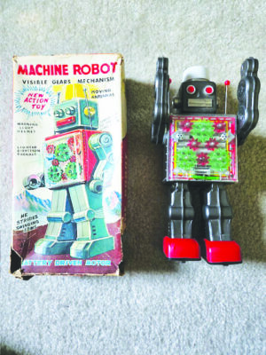 A classic red and gray robot toy is laid out next to the box that it came in.