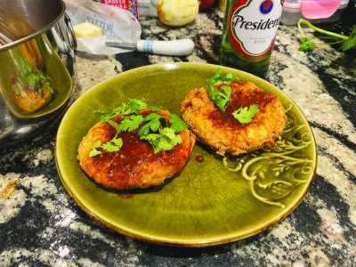 Spicy chicken patties topped with herbs and sauce on a green plate