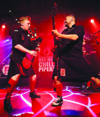 Two musicians play a Saxaphone and guitar in a red-lit venue