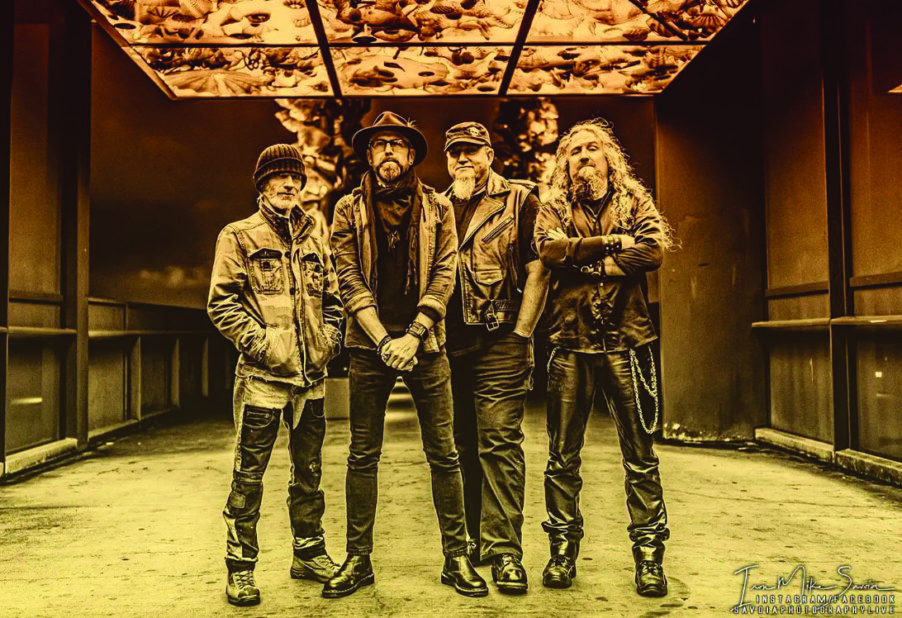 four male band members standing in large empty room, photo in sepia tones