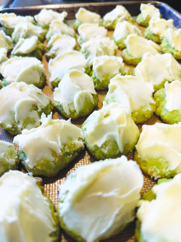 rows of small cookies covered in frosting sitting on baking sheet