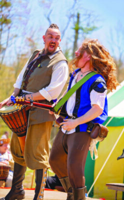 Two Renaissance Faire actors sing and dance for a crowd