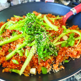 Plate with fried rice covered in cooked green vegetables