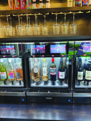 A DIY wine dispenser, with four various bottles on display.
