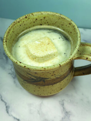 ceramic mug sitting on counter filled with hot drink and melting marshmallow