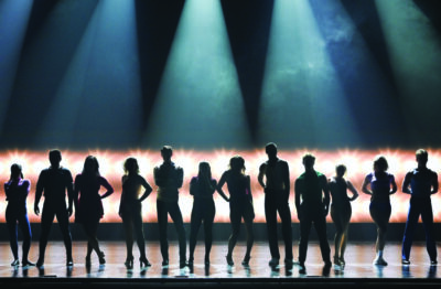 A line of silhouettes pose dramatically on a stage