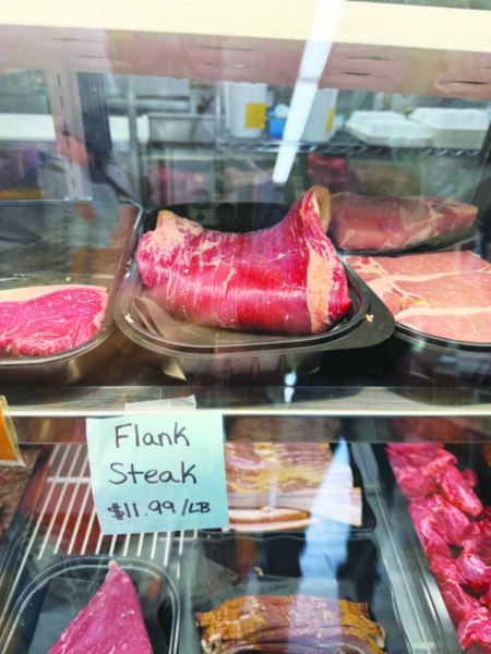 folded, thin piece of uncooked meat on shelf in marketplace, refrigerated meat case