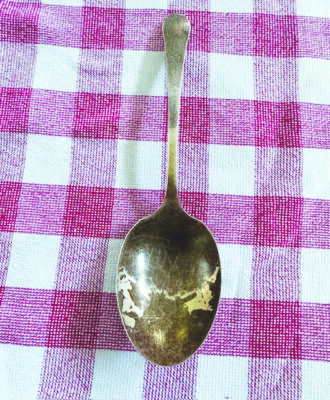 a tarnished silver spoon on a red checked table cloth