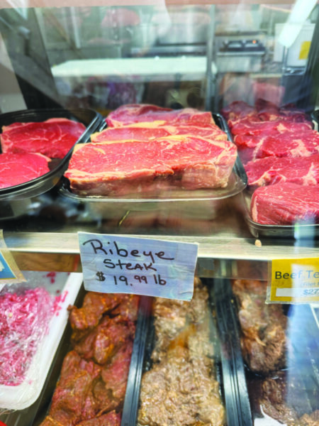 uncooked flat cut of meat with veins of fat, sitting in refridgerated retail case