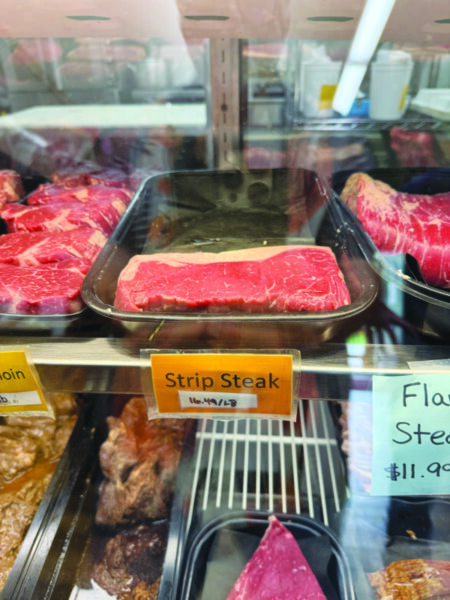 flat piece of uncooked meat on shelf in refrigerated case with other meats