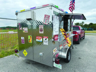 back of a small food truck hooked up to a red truck