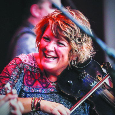 A woman smiles broadly as she plays the violin at an Irish Fest