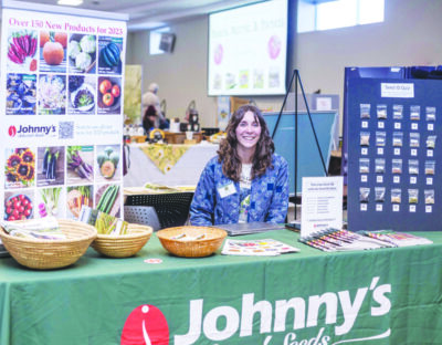woman sitting behind table at event, baskets and piles of seed baskets