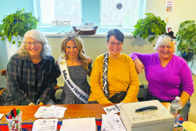 three woman and Miss NH wearing her sash and crown, sitting behind table, smiling