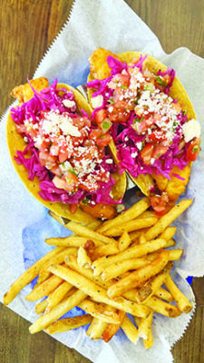 fish tacos on wrapper with pile of french fries