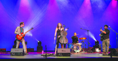 four member band playing on stage with singer/cellist front woman