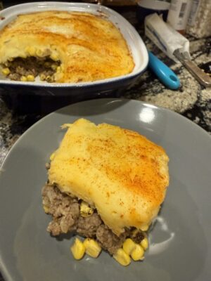square of shepherd's pie with mashed potato crust over ground beef and corn on plate