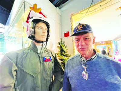 elderly man standing next to mannequin wearing pilot's uniform