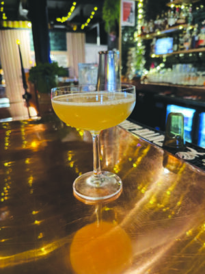 a stemmed, bowl shaped cocktail glass filled with a light cocktail, sitting on a bar top