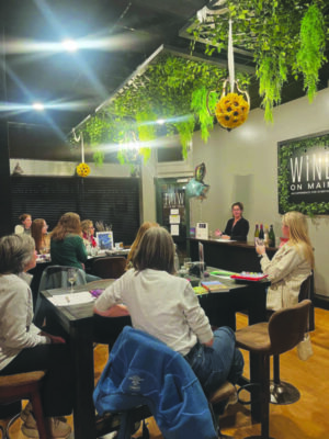women sitting at tables in large retail space, drinking wine