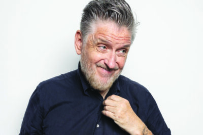 portrait of elder man grinning and giving a knowing look