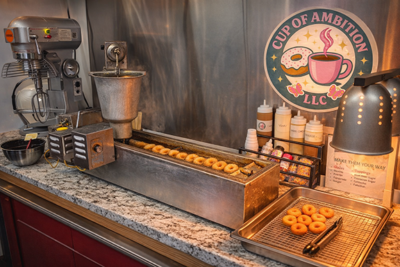 Counter with long doughnut making machine, doughnuts on conveyer belt