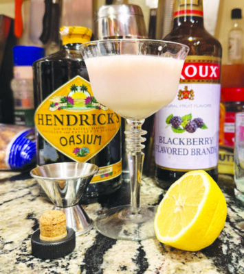 stemmed cocktail glass with cloudy cocktail on counter surrounded by ingredients