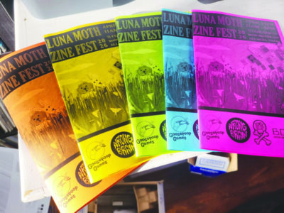 black and white zines printed on bright different colored papers, fanned out