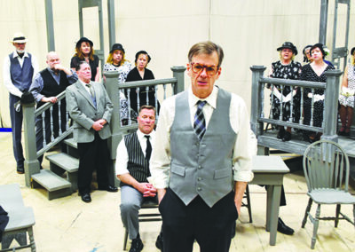 group of people on stage, man wearing suit in foreground