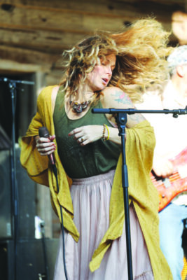 woman in front of microphone swaying to the music, head thrown to the side and hair blowing