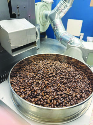 metal container of coffee beans sitting on counter near machinery