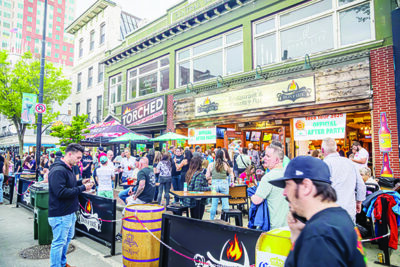crowd of people outside of restaurant, some standing in line, sunny evening on downtown sidewalk