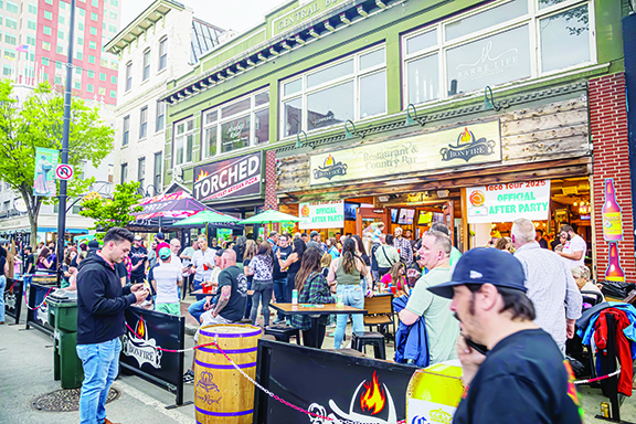 crowd of people outside of restaurant, some standing in line, sunny evening on downtown sidewalk