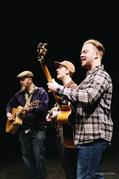 three men playing guitars on dark background