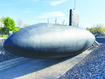 submarine sitting on pavement in enclosed area in outdoor exhibit