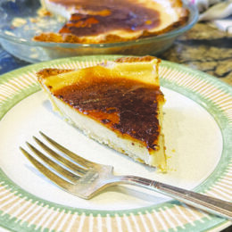 piece of wedge shaped, creamy pie with dark topping, on plate with fork