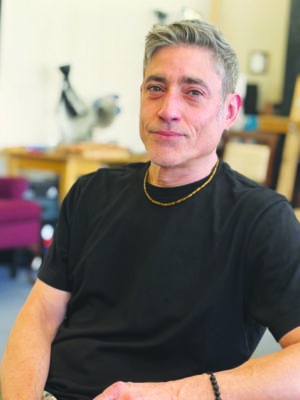 middle aged man wearing black shirt, coifed hair, small smile