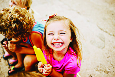 Group of Kids Eating Frozen Colorful Popsicles in the Summer