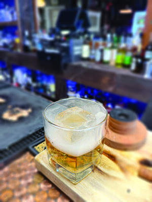 cocktail in short glass sitting on bar counter, smoke at top of glass