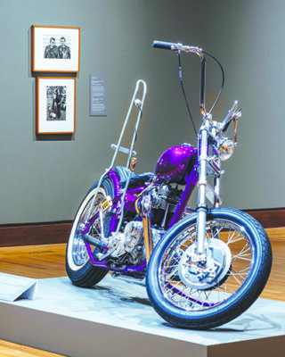 retro motorcycle displayed in museum, photographs on walls behind