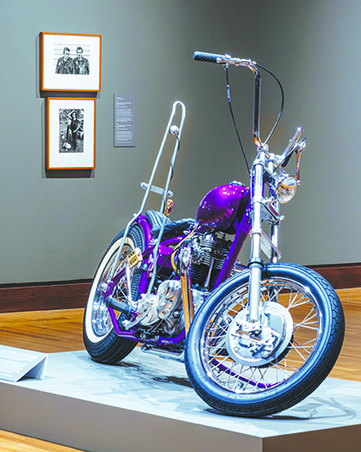 retro motorcycle displayed in museum, photographs on walls behind