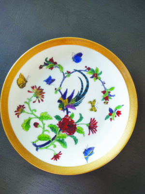 plate seen from above, painted with flowers, butterflies, and colorful birds