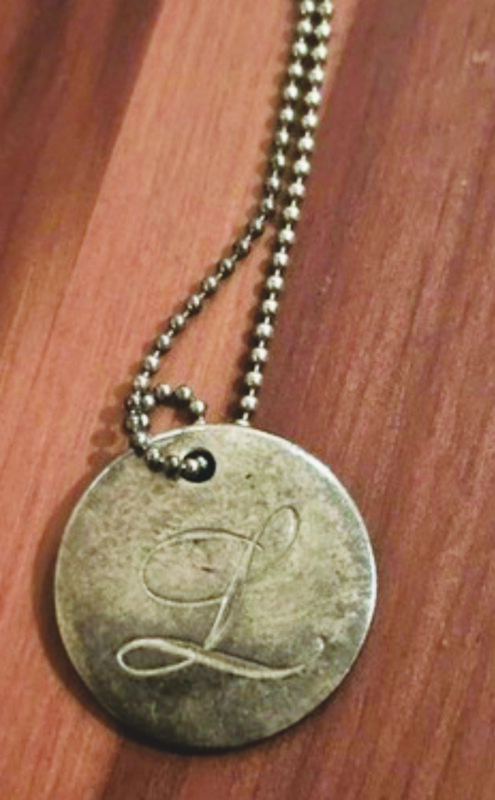 silver disc with etched letter "L", hanging off ball chain