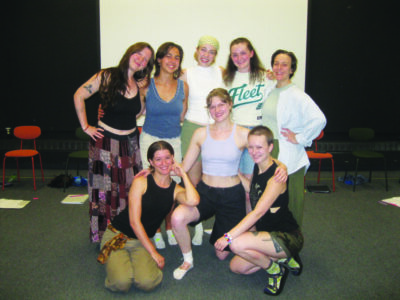 cast of eight women actors posing together in rehearsals