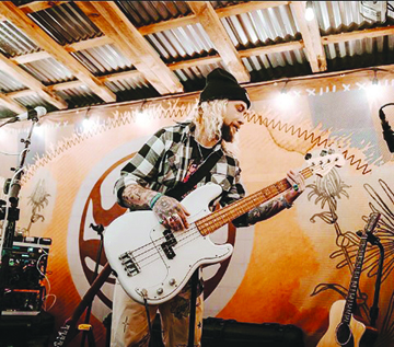 white man on small stage playing guitar