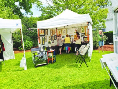 event tent on grassy lawn, filled with paintings, art festival