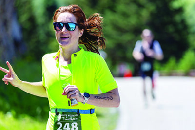 woman wearing bright green shirt with number tag tied around her waist. running road race on sunny day