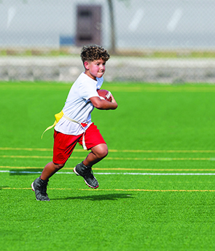 Cute athletic little boy playing excitedly in a flag football game