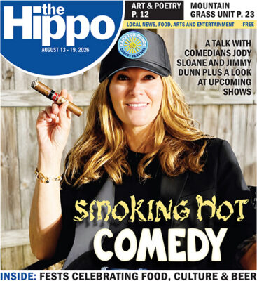 front page of Hippo showing comedian Jody Sloan sitting outside and holding up a cigar